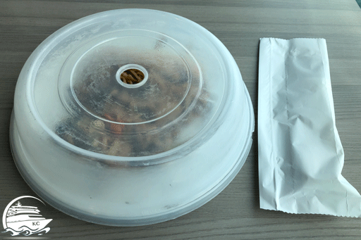 Teller mit Abdeckung und abgepacktes Besteck. Die Speisen werden mit einem Plastikdeckel abgedeckt. Das Besteck bekommt man in einer Papiertüte.